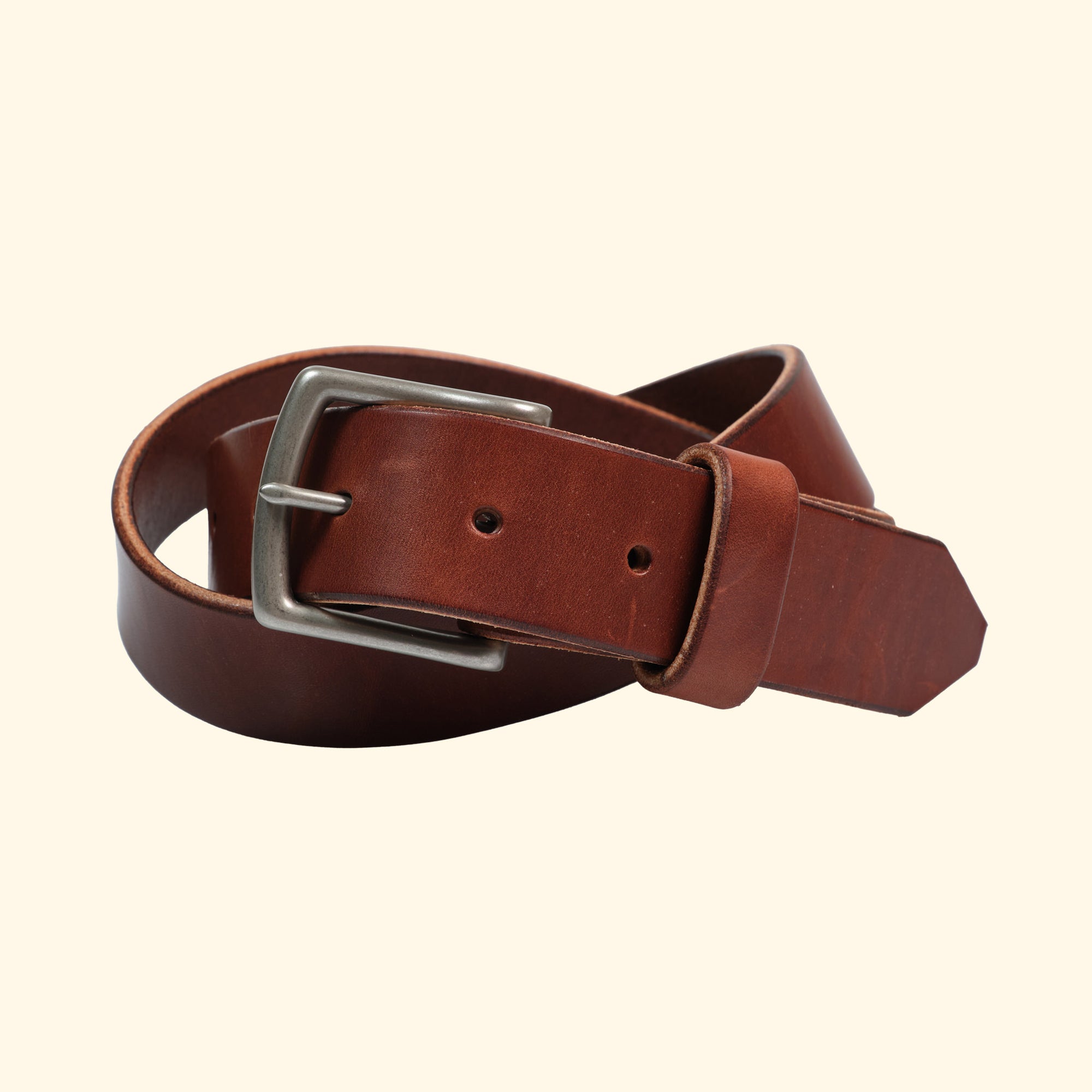 Zusammengewickelter Ledergürtel aus Wickett & Craig 'Traditional Harness' Leder in Medium Brown. Sichtbar ist die silberne Messingschnalle, die den eleganten und robusten Charakter des Gürtels unterstreicht.